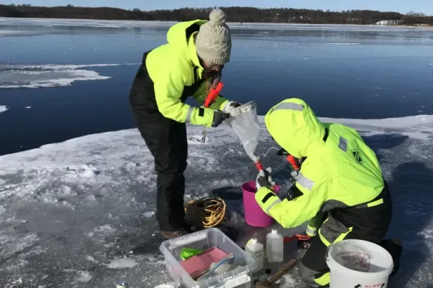 Two people by a lake in winter. Photo.