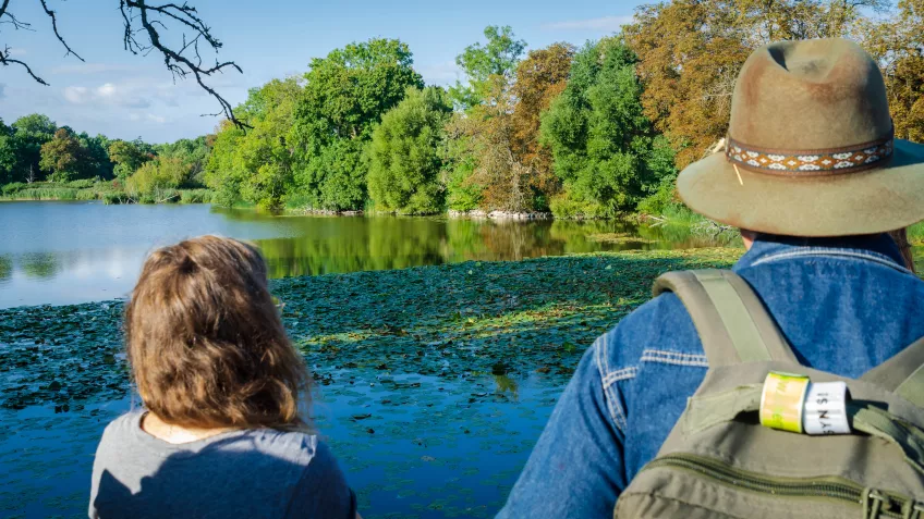 Two people are standing looking out over a lake. Photo.